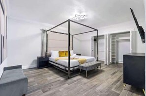 Une chambre à coucher moderne avec un lit à baldaquin, une table de chevet, un banc et une armoire.