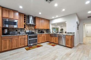 Eine moderne Küche mit Holzschränken, Edelstahlgeräten und einer Marmorarbeitsplatte.