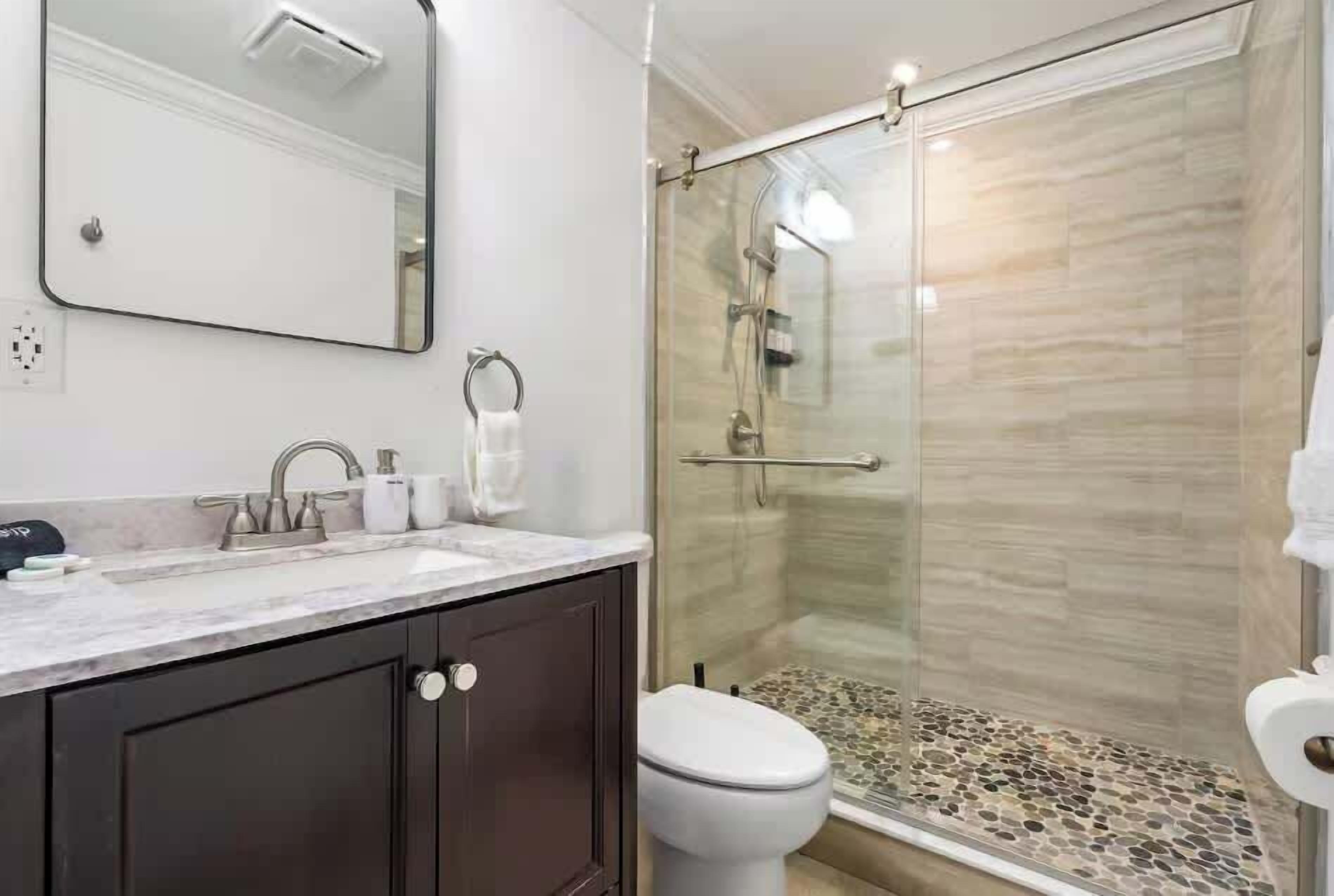 Een badkamer met douche, toilet en wastafel.