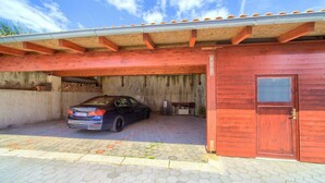Ein Auto, das unter einer Garage mit roter Tür geparkt ist.