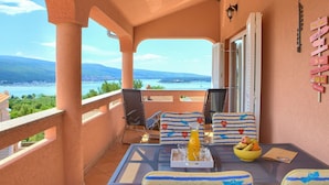 Ein Balkon mit Tisch, Stühlen, einer Orangensaftflasche und einer Obstschale.