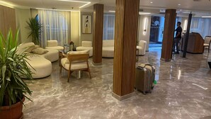 Una hall moderna con pavimento in marmo, sedute confortevoli, elementi in legno e un'area reception.
