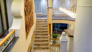 Un interno su più livelli con una scala, pannelli in legno alle pareti e un lampadario.