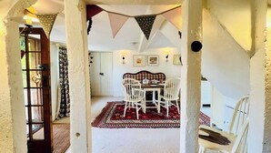 A dining area with a table and chairs, a patterned rug, and a door leading to another room.