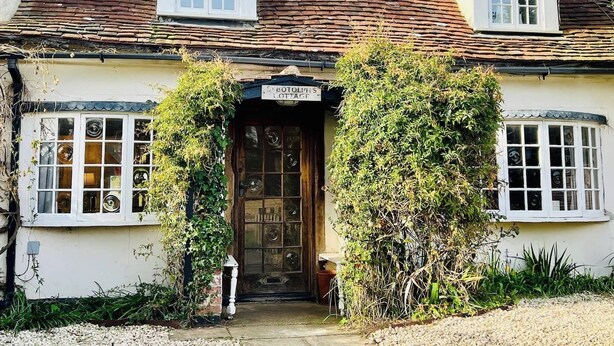 A traditional cottage with a tiled roof, a wooden front door, and a small porch area.