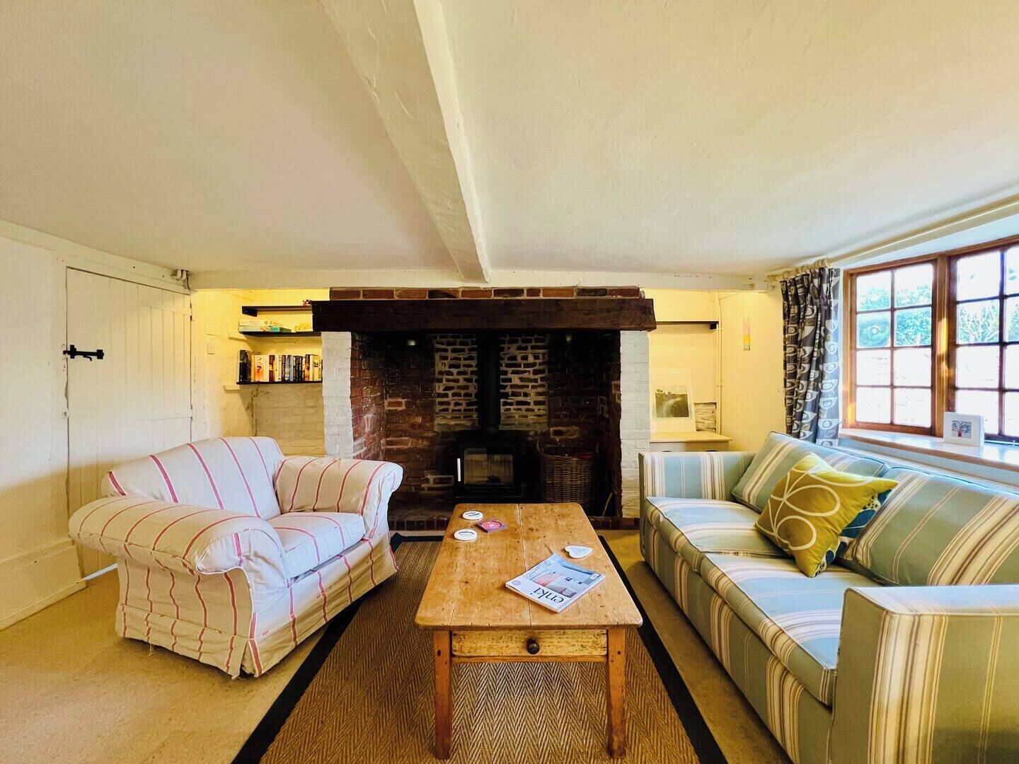 A living room with a fireplace, two sofas, a coffee table, and a bookshelf.