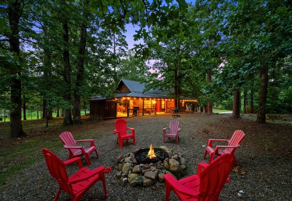 A cabin with a fire pit and red chairs in a forest setting. - ~2 Acres | Hot Tub | Fire Pit | Near Beavers Bend (Broken Bow)