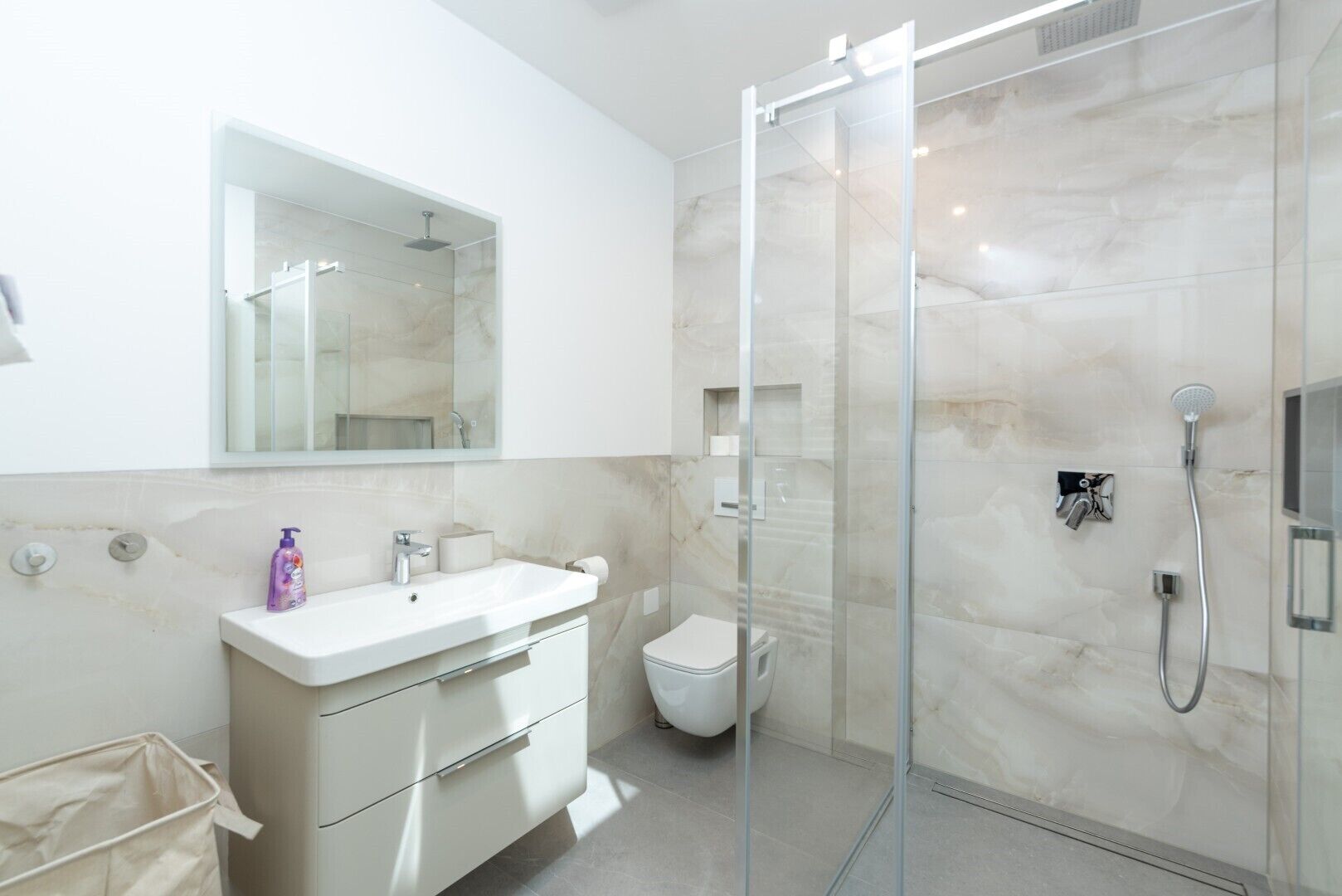 Une salle de bain moderne avec une douche à parois de verre, un lavabo blanc et des toilettes.