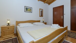Ein Schlafzimmer mit einem hölzernen Bett, Nachttischen, einem Schminktisch und einer Tür.