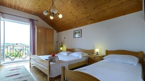 Ein Schlafzimmer mit zwei Betten, Holzboden und einem Balkon mit Blick.