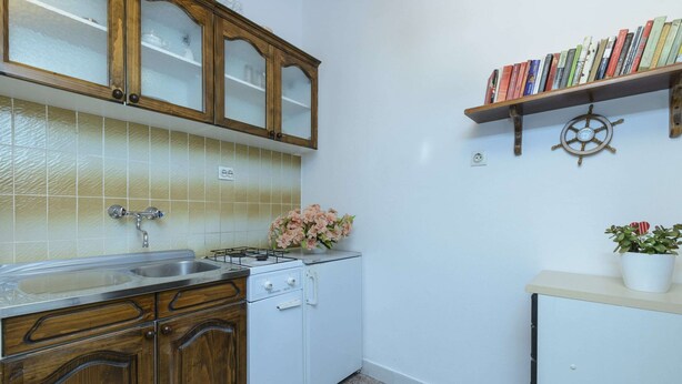 Eine Küche mit Holzschränken, einem weißen Kühlschrank, einer Spüle und einem Regal mit Büchern und einer Schiffsaegel-Dekoration.