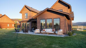 Une maison moderne dotée d’un grand patio, d’un espace salon extérieur et offrant une vue sur le paysage.