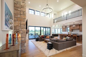 A spacious living area with a stone fireplace, a large sofa, and a dining area with a kitchen in the background.