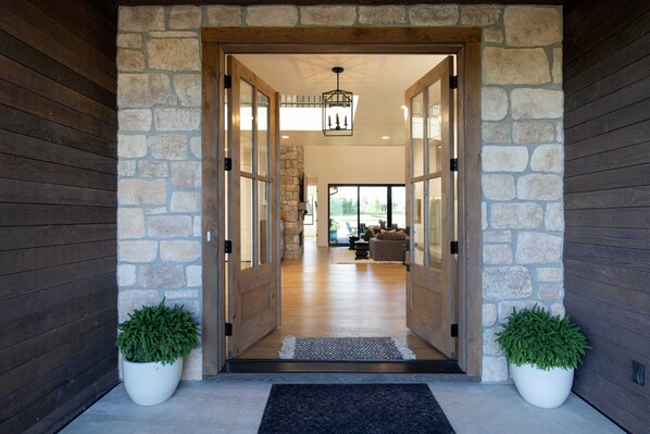 A stone entrance with a wooden door, a potted plant, and a view into a living area with a couch and a stone wall.