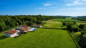 Paisaje rural con casas, piscina y campos verdes.
