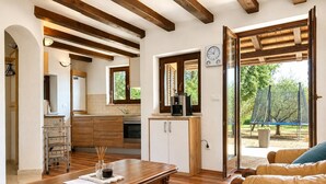 Un espacio habitable amplio con una mesa de comedor de madera, un sofá de cuero y una cocina con armarios de madera y horno empotrado.