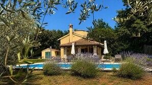 Una villa con piscina, rodeada de arbustos de lavanda y olivos.