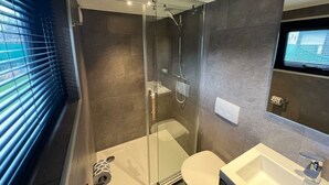 Un baño moderno con ducha acristalada, inodoro y lavabo.