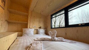 Una habitación de cabaña de madera con una cama, almohadas, una ventana y una toalla con forma de conejo.