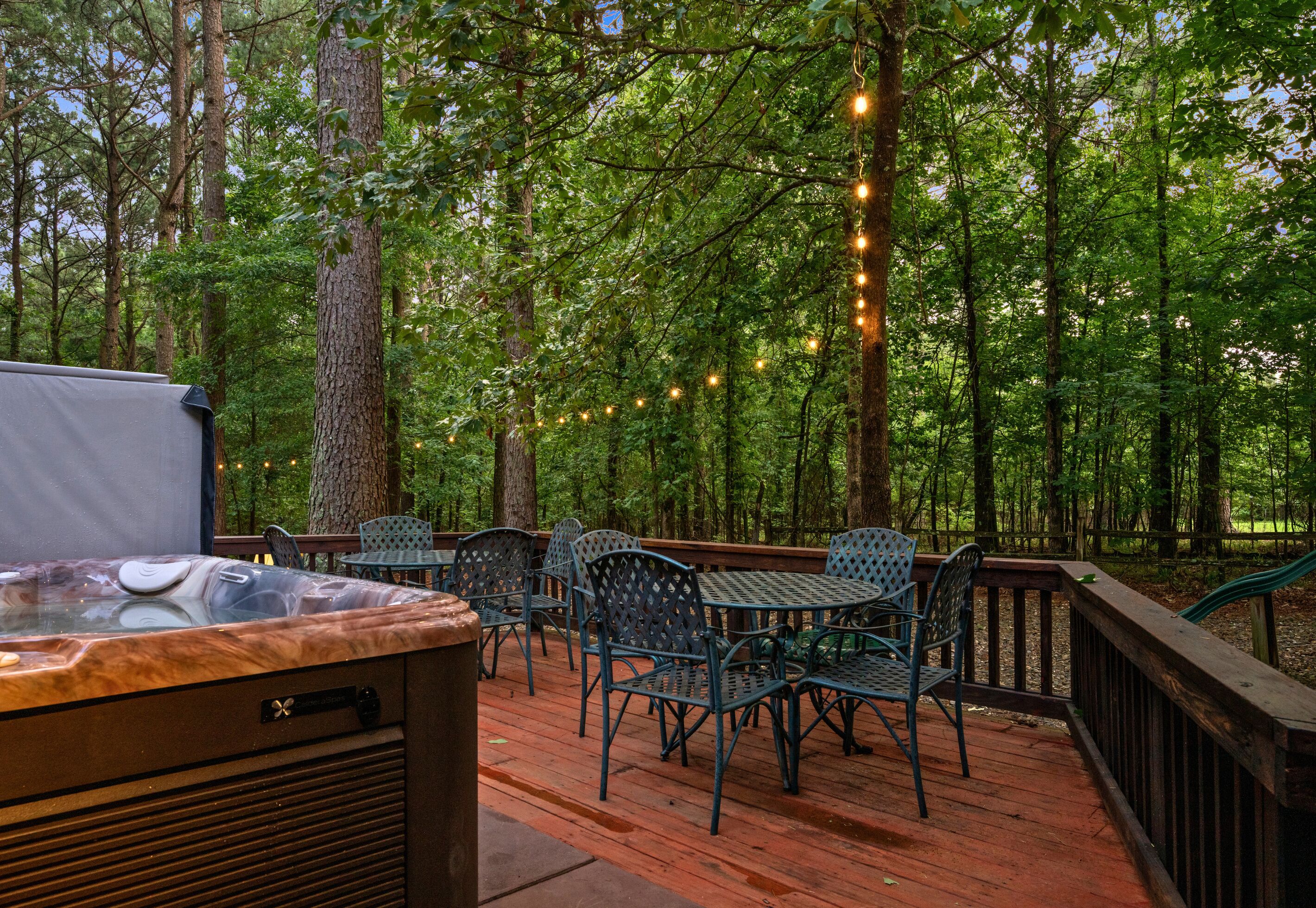 A deck with outdoor seating, a hot tub, and string lights.
