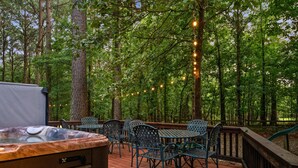 Una terraza con asientos exteriores, un jacuzzi y luces colgantes.