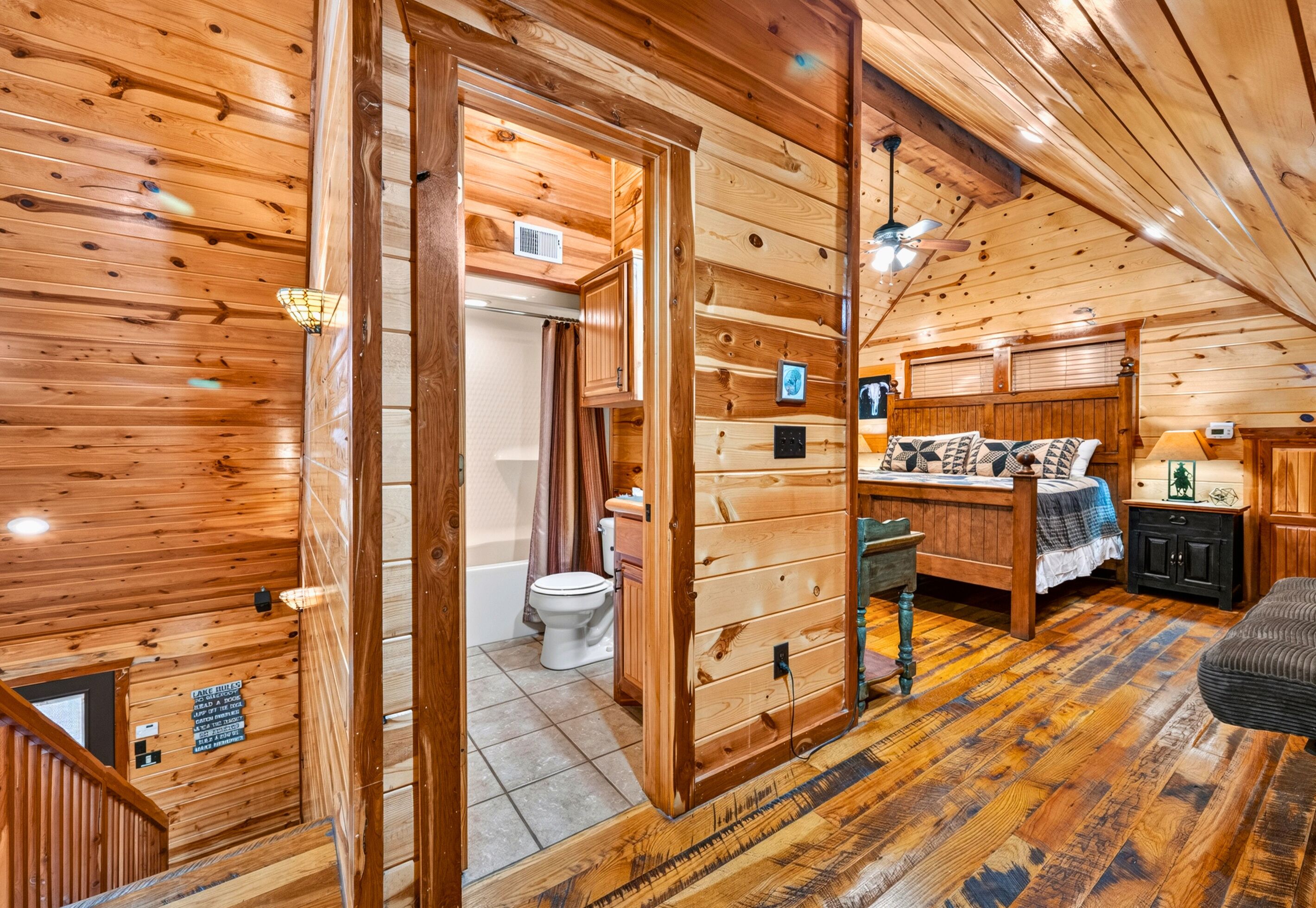 A wooden interior with a bed, a bathroom, and a staircase.