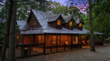 A log cabin with a metal roof, wooden deck, and a fenced area.