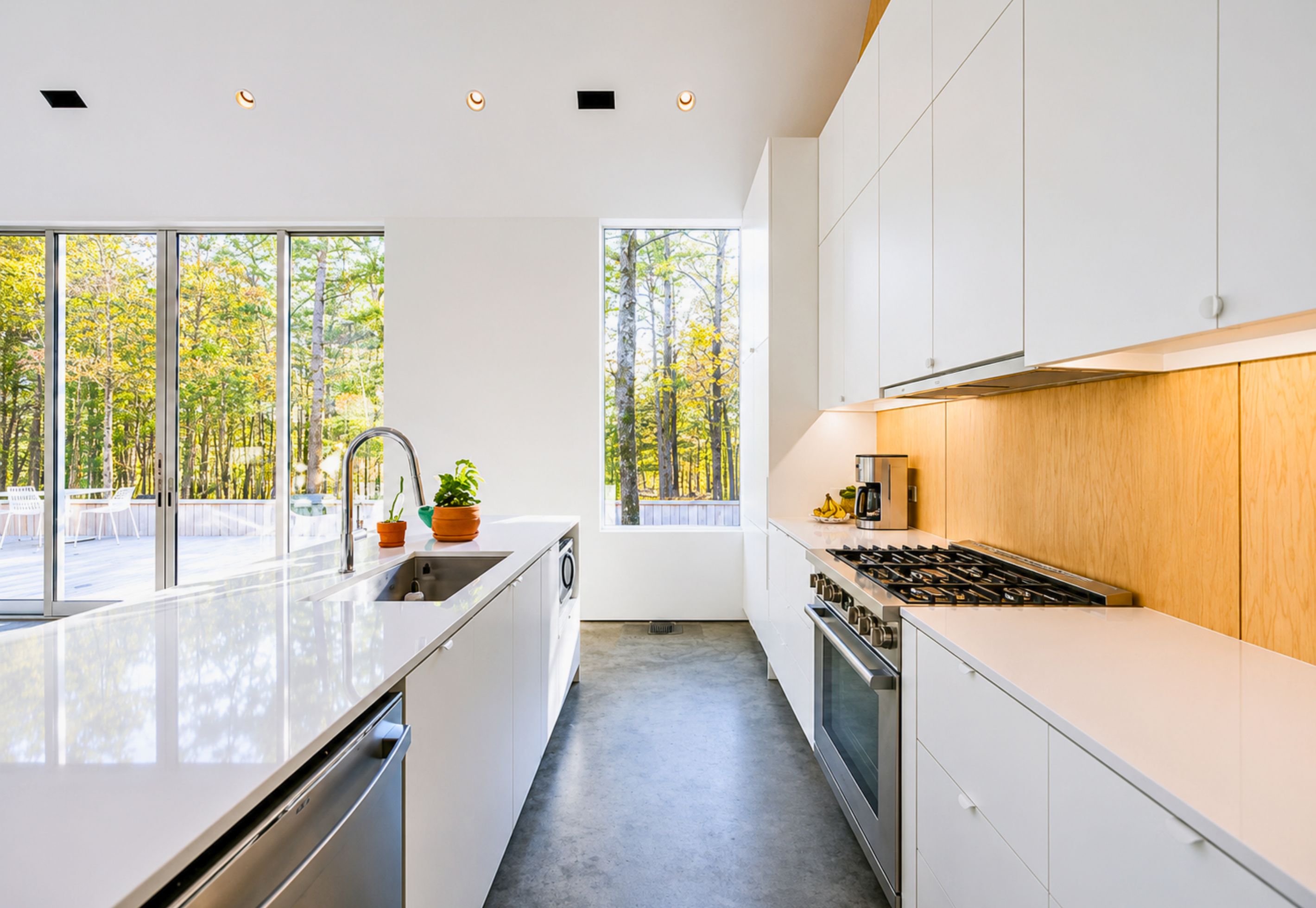 A modern kitchen with a large window, stainless steel appliances, and a view of trees.
