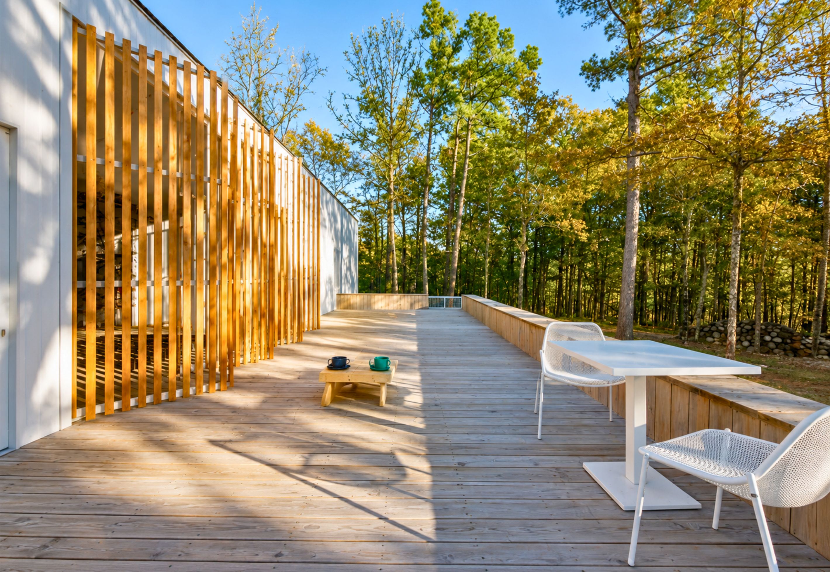 A wooden deck with outdoor seating and a view of a forest.