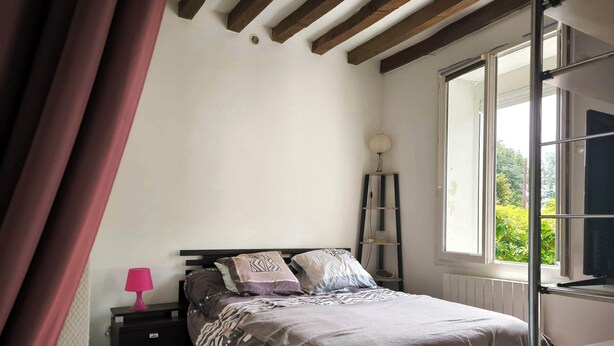Een slaapkamer met een bed, nachtkastje, lamp, plank en raam.
