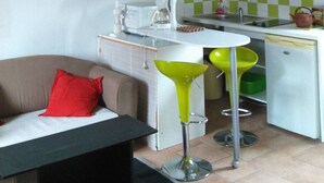 Een kleine keuken met een eethoek, een rode lamp en een raam met planken.