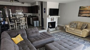 A modern living room with a sectional sofa, a beige sofa, and a fireplace.