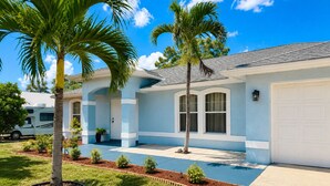 A residential property with a swimming pool, palm trees, and a white RV parked in the driveway. - Pool Home/ Tropical Paradise Getaway Near Beaches and Downtown Fort Myers (Fort Myers)