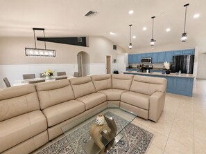 Eine moderne Küche mit blauen Schränken, einer großen Kochinsel und einem beigefarbenen Ecksofa.