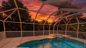 A swimming pool with a geometric roof structure, surrounded by a white fence and lush greenery. - Pool Home/ Tropical Paradise Getaway Near Beaches and Downtown Fort Myers (Fort Myers)