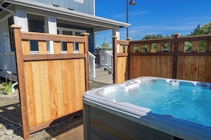 Et træhegn omgiver en jacuzzi med uhindret udsigt til et hus i baggrunden.