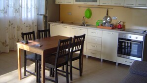 A compact kitchen with a dining table, chairs, a refrigerator, a stove, and a sink.