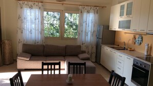A cozy living area with a sofa, a dining table, and a kitchen with white cabinets and appliances.