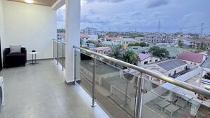 Een balkon met uitzicht op een woongebied, een stoel en een klein tafeltje.