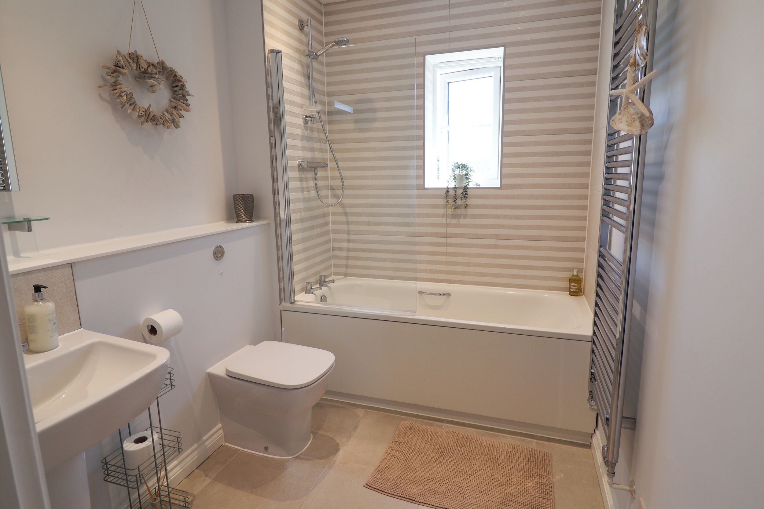 A modern bathroom with a shower, toilet, sink, and a window providing natural light.