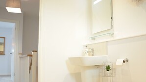 Ein Badezimmer mit Toilette, Waschbecken, Spiegel und einer kleinen Pflanze.
