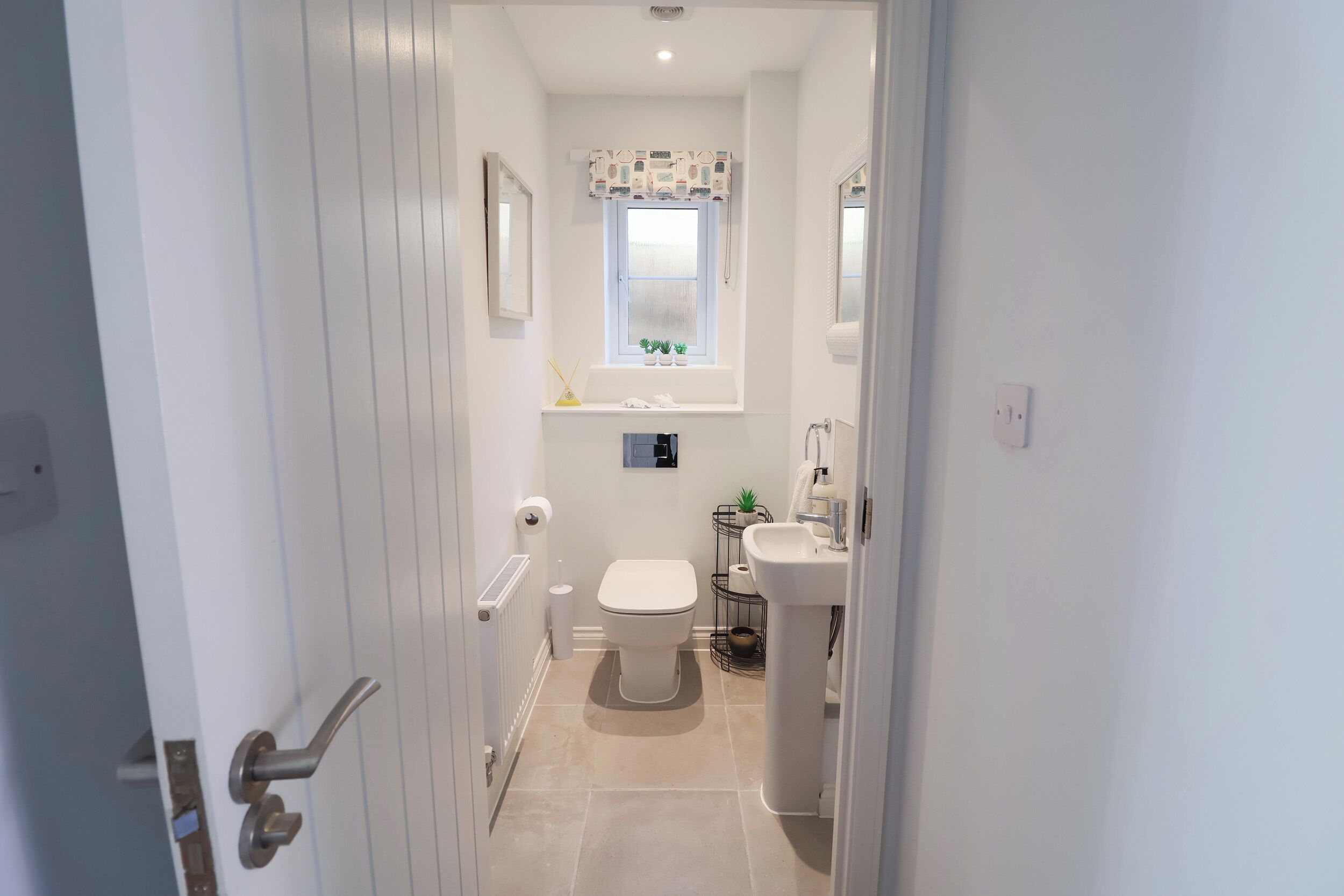Et moderne badeværelse med toilet, vask og et vindue med en plante.