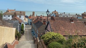 Eine Küstenstadt mit traditioneller Architektur, freiem Blick auf das Meer und einer schmalen Straße, die zum Wasser führt.