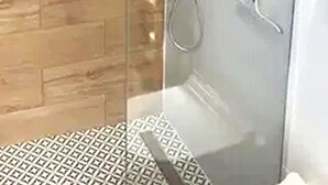 A glass-enclosed shower with a wooden floor and a patterned mat. - Charming apartment in lovely Toruń perfect for your getaway (Toruń)