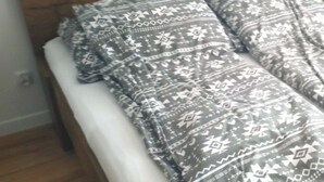 A bed with a patterned blanket and pillows, a wooden headboard, and a wooden floor. - Charming apartment in lovely Toruń perfect for your getaway (Toruń)