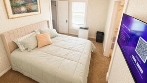 Ein Schlafzimmer mit einem Bett, einem Gemälde, einem Fernseher und einer Tür.