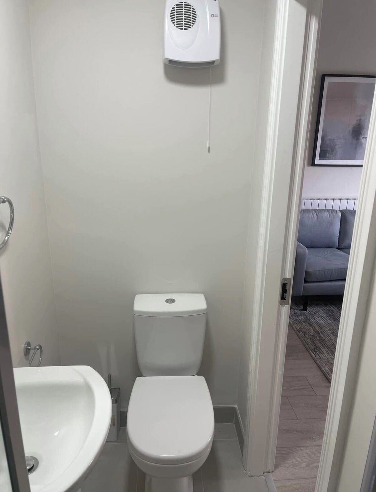 A small bathroom with a toilet, sink, and a wall-mounted air purifier.
