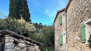Ein Steinhaus mit rustikalem Aussehen, einem kleinen Rundbogenportal und einem schmalen Weg, der zu einer Tür führt.