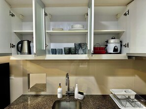 A kitchen with a sink, a kettle, a dish rack, and a Crock Pot. - Enjoy comfortable & spacious stay, perfectly located in the vibrant heart of BGC (Taguig)