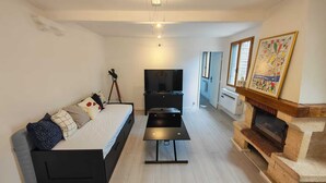 Uma sala de estar com sofá, televisão, lareira e um quadro na parede.